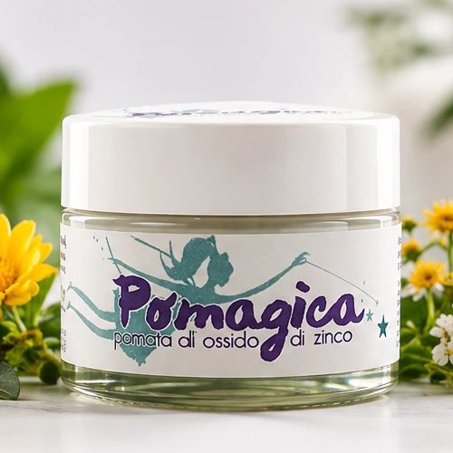 Confezione di Pomagica: la scatola e il vasetto di pomata all'ossido di zinco, tra fiori ed erbe secche